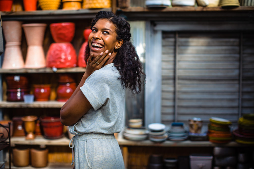 picture of Samantha, an African American girl smiling with colorful pottery behind her