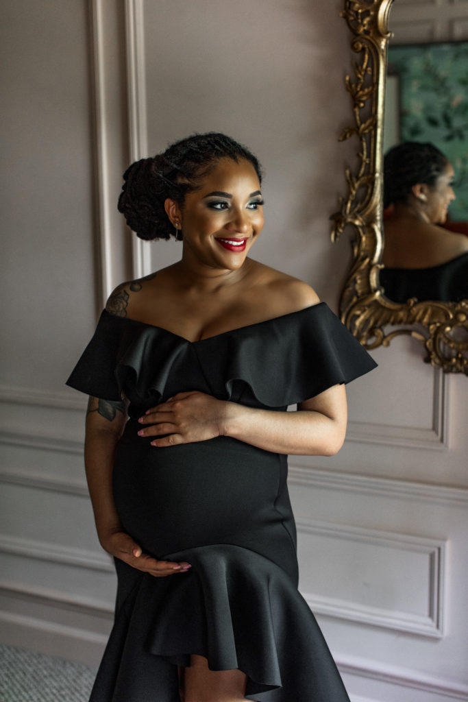 Black pregnant female poses for an in home maternity session in an eclectic bedroom.