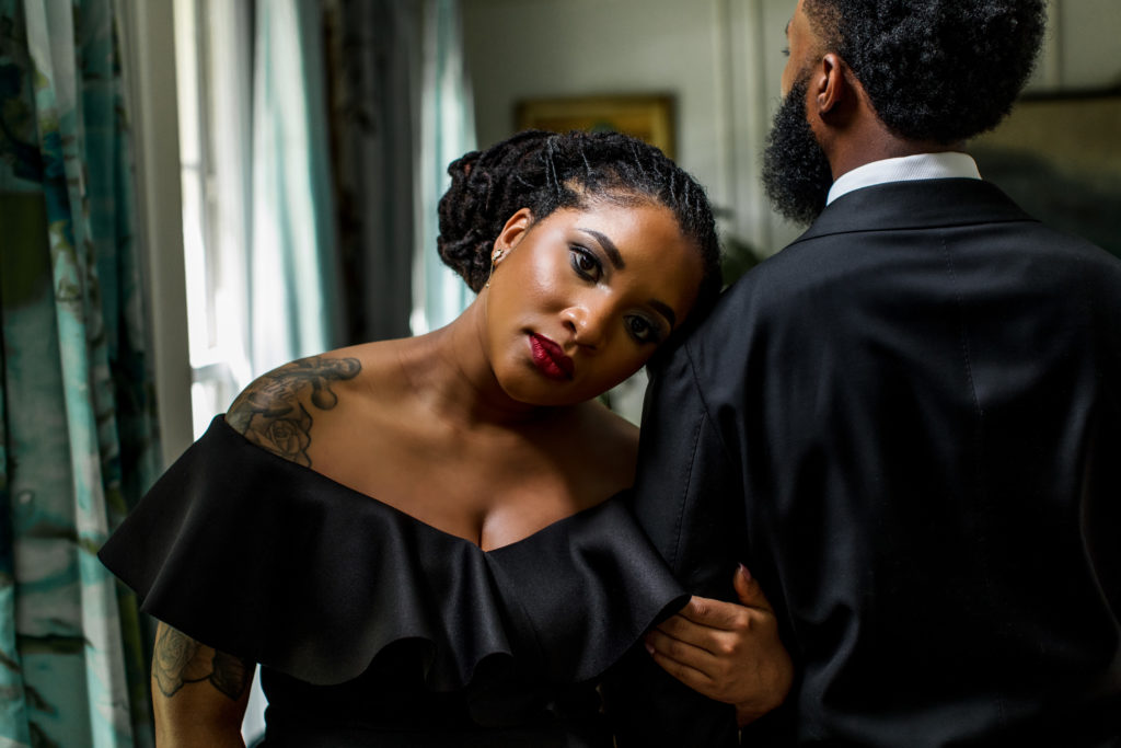 Couples portrait session of a  black couple dressed up in in a black suit and dress for their couples photo session.